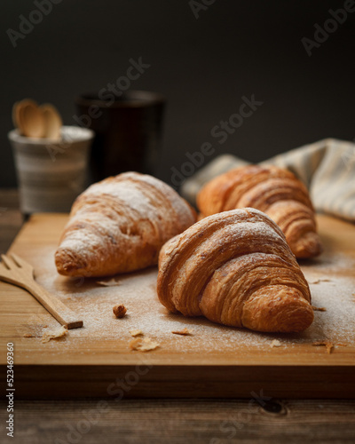 Croissant with icing sugar on wood table
