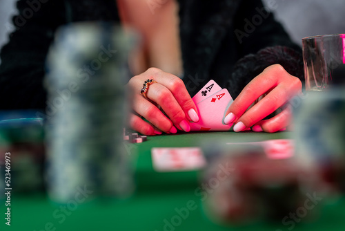 young woman is holding gambling chips and casino cards at the table in a beautiful dress.