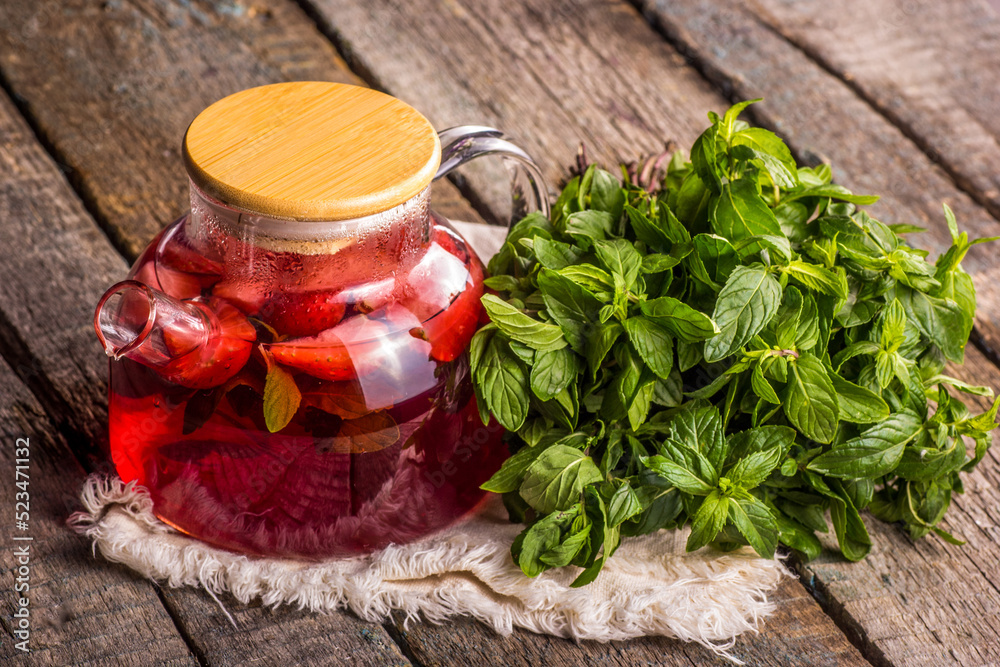 Teapot of summer fruit tea. Red tea and mint leaves