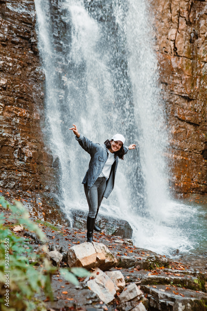 Obraz premium young pretty woman hiking enjoying view of waterfall