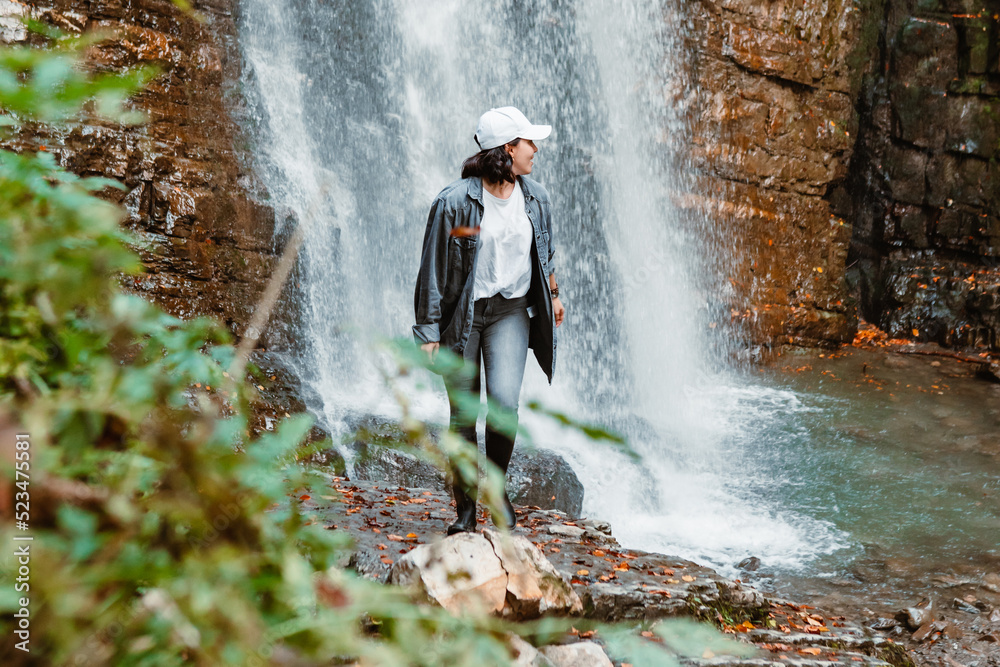 Obraz premium young pretty woman hiking enjoying view of waterfall