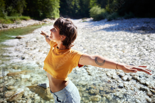Smiling woman standing with arms outstretched on sunny day photo