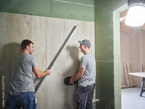 Happy tilers lifting large ceramic tiles onto wall with vacuum suction cups photo