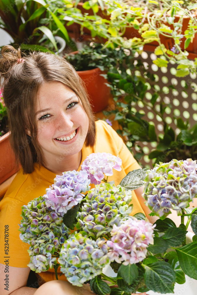 Happy girl with hydrangea flowers on balcony