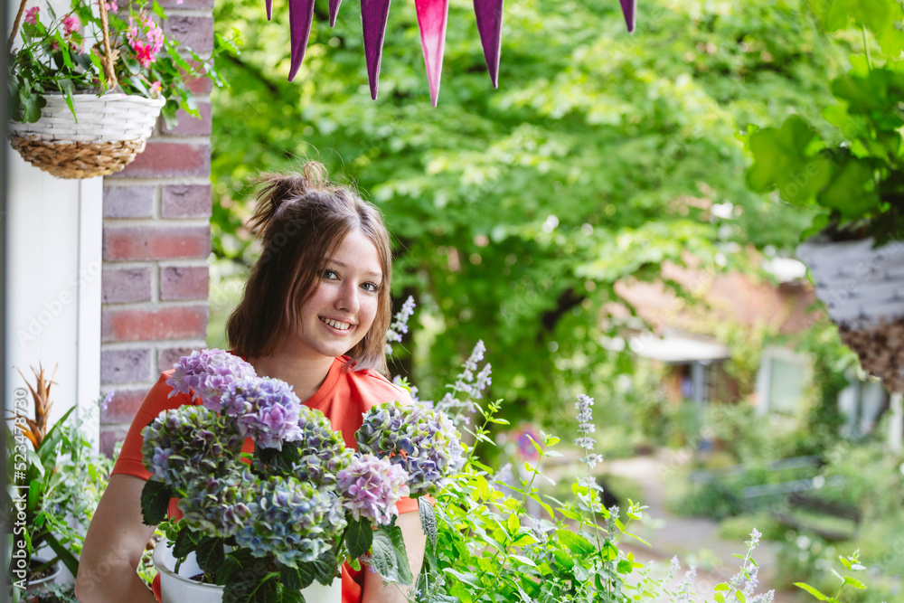 Smiling teenage girl with hydrangea flowers on balcony Smiling teenage girl with hydrangea flowers on balcony