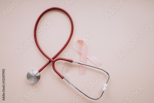 Pink ribbon and stethoscope on a pink background. Top view. Breast cancer awareness concept