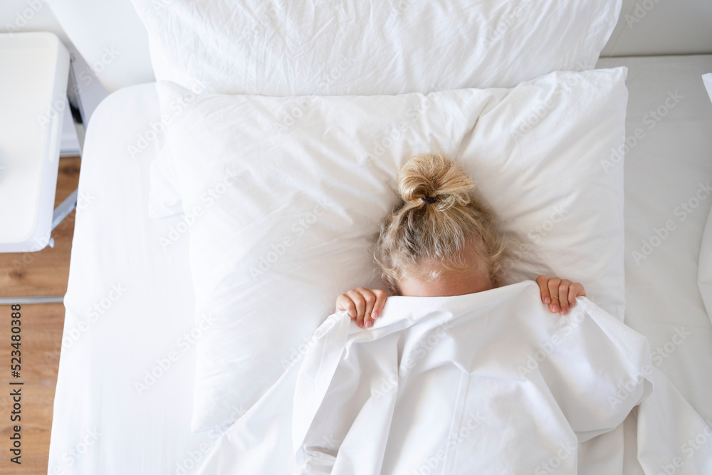 Girl hiding face with blanket in bed Girl hiding face with blanket in bed