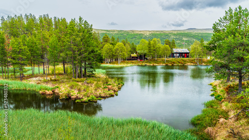 Norway, Innlandet, Lake in Rondane National Park with secluded hut in background photo