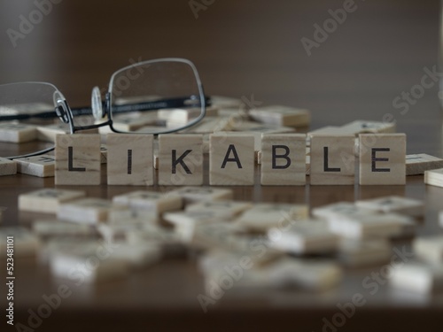 Likable word or concept represented by wooden letter tiles on a wooden table with glasses and a book photo