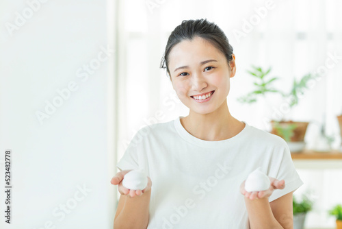 洗顔の泡を手に乗せる若い女性 © japolia
