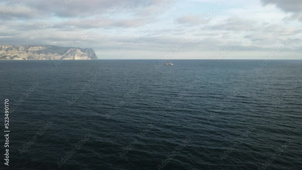 Aerial view from above on calm azure sea and volcanic rocky shores. Small waves on water surface in motion blur. Nature ocean sea beach background. Nobody. Aerial flying drone view over the sea ocean.