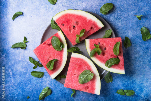 Sliced watermelon on an old blue background with mint and ice
