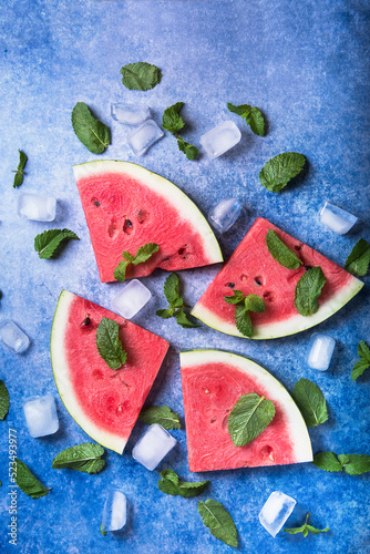 Sliced watermelon on an old blue background with mint and ice