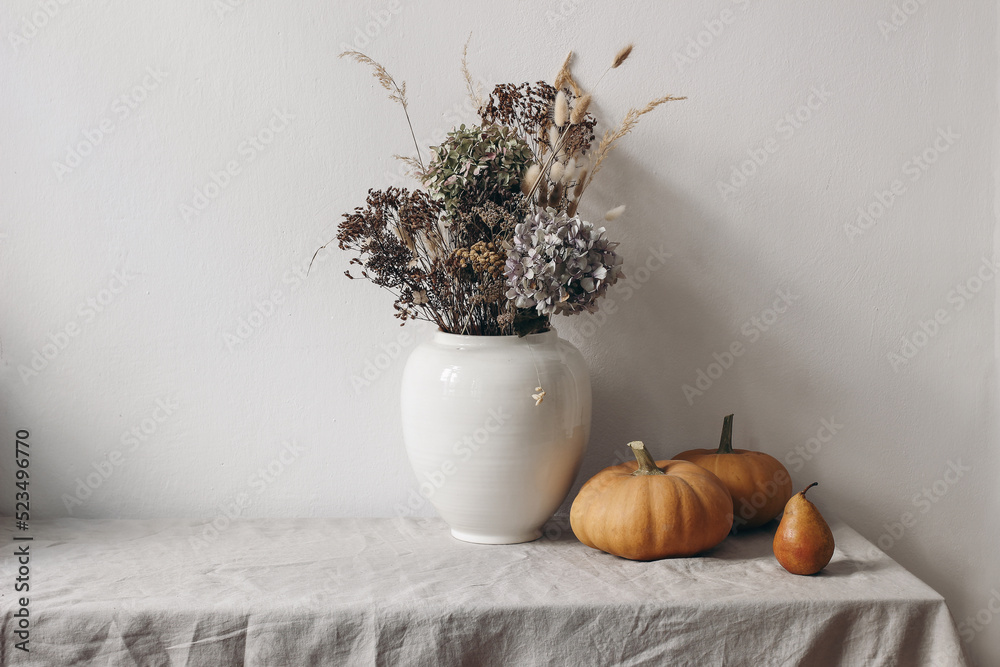 Autumn, fall still life. Big ceramic vase with dry hydrangea flowers, grass  boho bouquet. Orange pumpkins and pear fruit on linen table cloth. White  wall background. Halloween, Thanksgiving holiday Stock-foto | Adobe