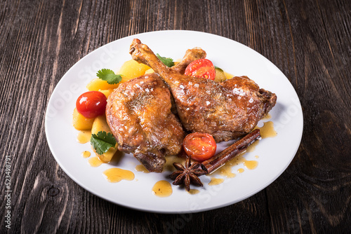 Duck legs with apples in orange sauce on a wooden background