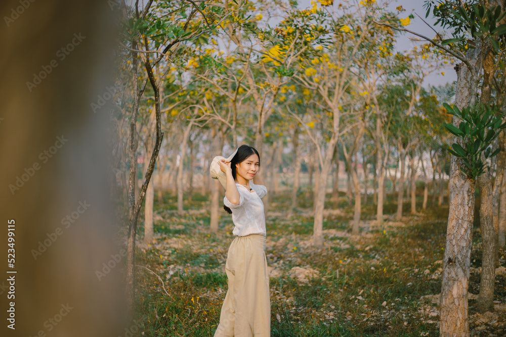 woman stands through a park full of trees at sunset
