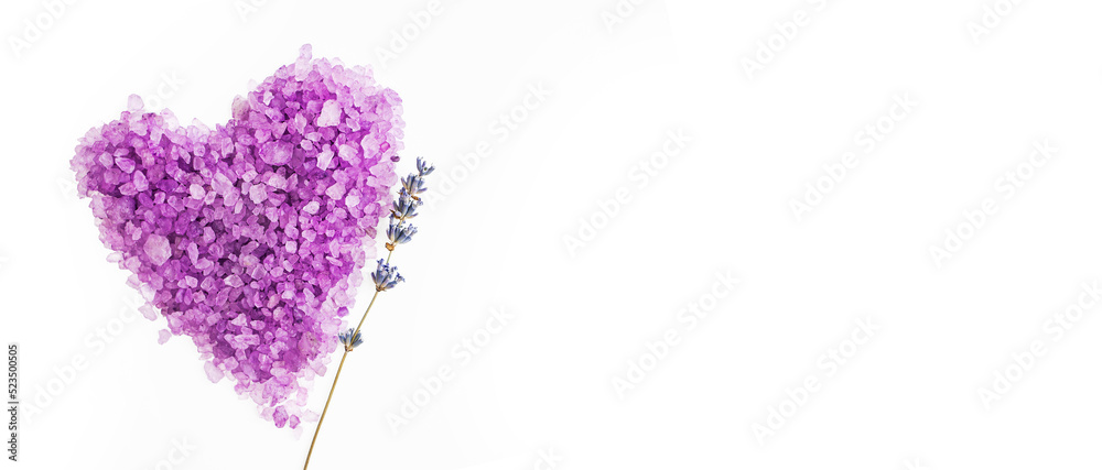 Lavender salt for spa treatments in the shape of a heart on a white background with a branch of natural lavender. Banner, flat lay, place for text.