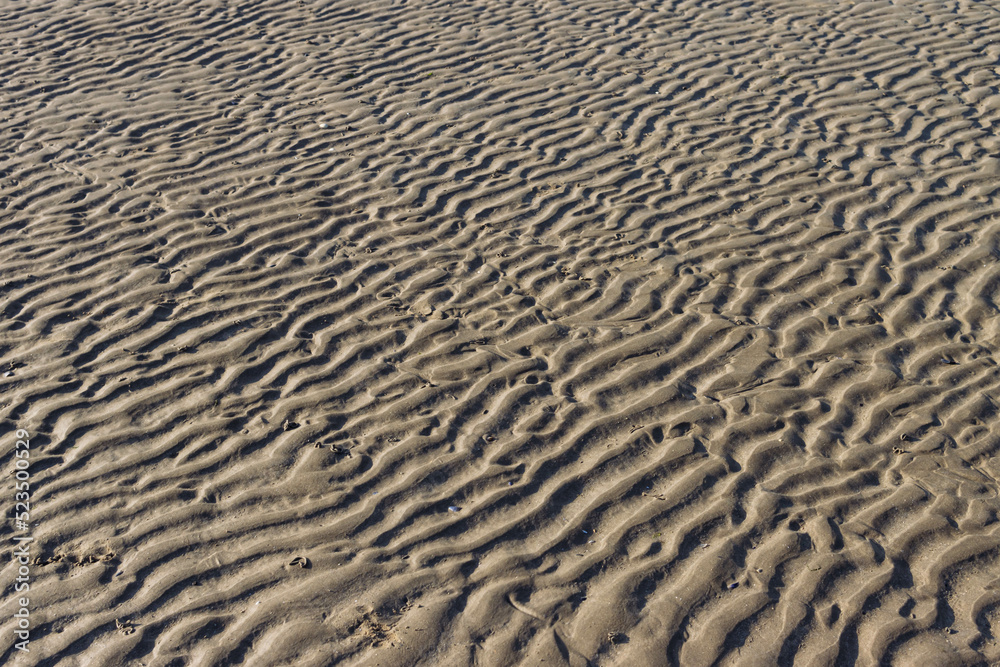 the background of the sand is ribbed and wet after the tide of water on the empty beach. There is a place for the inscription Beautiful landscape and splash the background of the sand is ribbed and wet after the tide of water on the empty beach. There is a place for the inscription Beautiful landscape and splash
