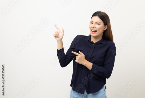 Young beautiful woman pointing finger to copyspace. Happy cheerful female on isolated white background. Pointing to blank space for advertise text.