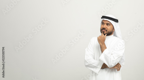 Portrait of arabic man with kandura dress on isolated white background. Arab business people thinking. photo