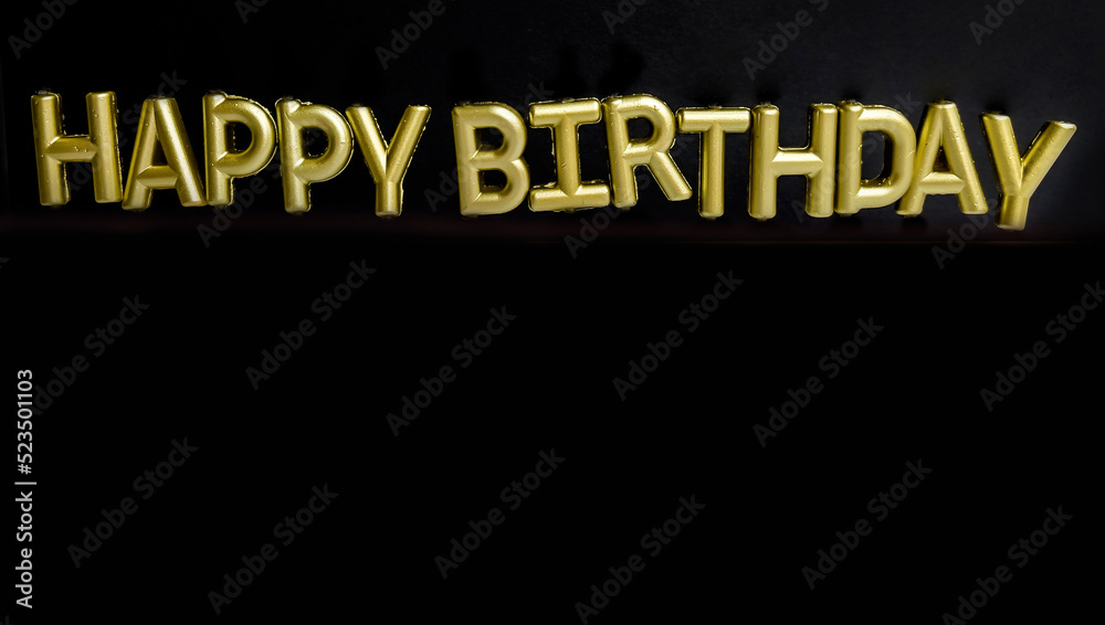 Fototapeta premium Golden Happy birthday sign with candles on black background 