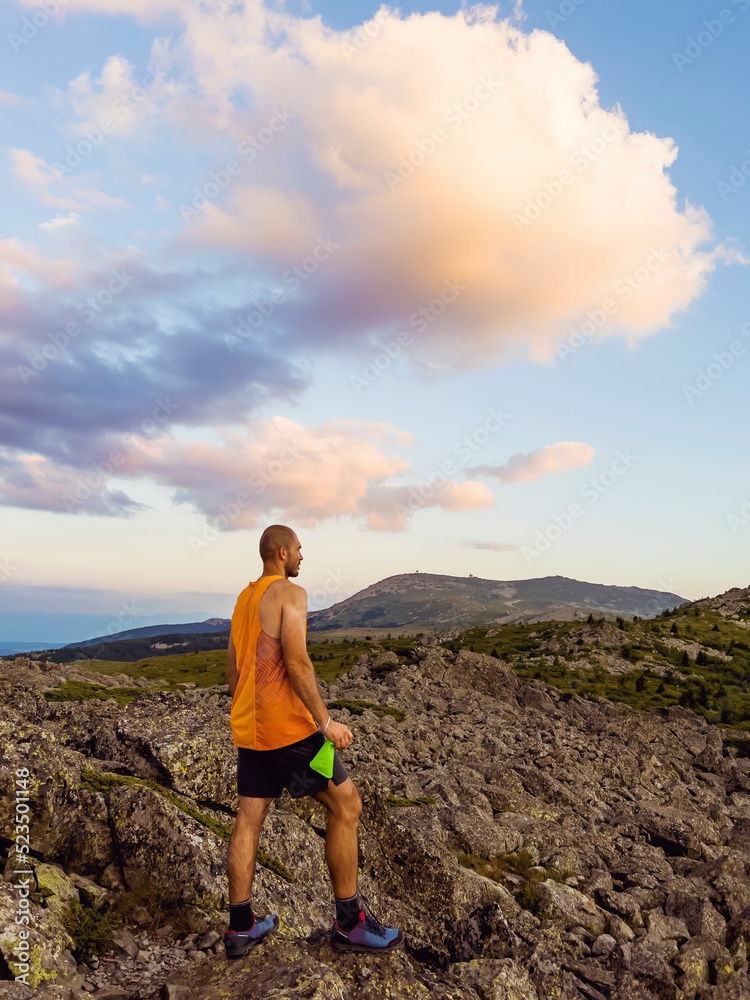Man Standing on  a Rocks  in High Mountain with Orange Sunset Cloudy Sky  .Vitosha Mountain ,Bulgaria 
