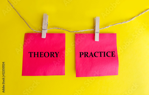 Theory and practice words . Wooden clothespins with red sticky notes with Words theory and practice on yellow background 