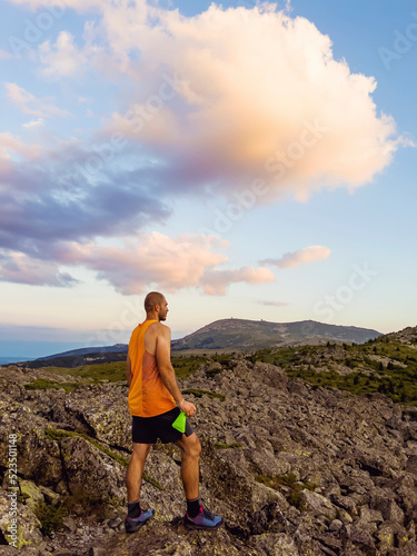 Man Standing on a Rocks in High Mountain with Orange Sunset Cloudy Sky .Vitosha Mountain ,Bulgaria 