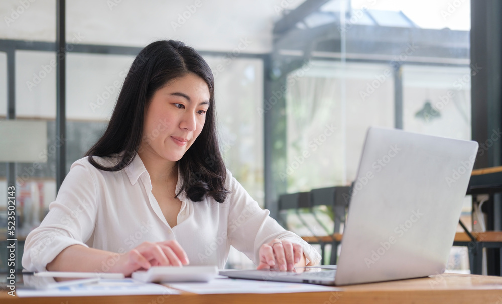 Focused female accountant working with laptop and using calculator for calculating finance taxing and statistics. Focused female accountant working with laptop and using calculator for calculating finance taxing and statistics.
