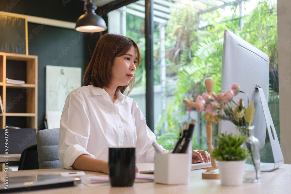 Concentrated asian female office worker working with computer at modern workplace. Concentrated asian female office worker working with computer at modern workplace.
