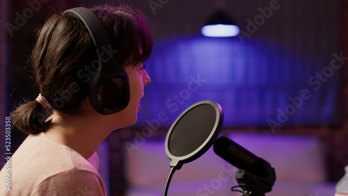 Closeup of famous influencer in online radio show talking with male host about social media success using professional microphone. Woman having casual converstion while recording podcast. photo