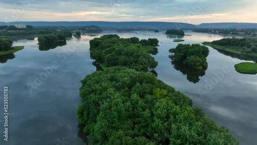 Small green islands covered with trees in middle of river. Colorful sunrise light reflects on still quiet water. Aerial view. photo