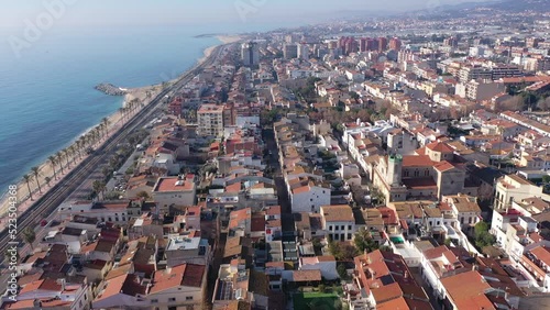 Scenic aerial view of coastal area of Spanish city of Vilassar de Mar overlooking brownish roofs of buildings and sandy seashore on sunny winter day, Catalonia photo