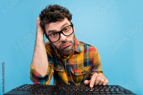 Photo of upset tired freelancer in specs dressed checked shirt look at webcam on remote video call isolated on blue color background photo