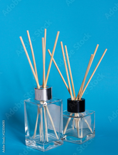 two bottles for home perfumes with incense sticks on a blue background
