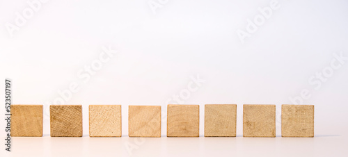 Acht quadratische Holzsteinen in einer Reihe vor weißem Hintergrund als Vorlage oder Mockup. Leere Scrabblesteine. photo