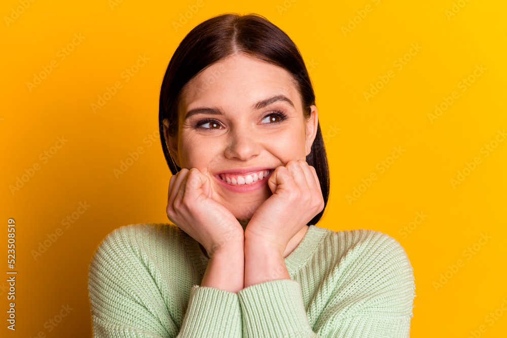 Photo of young cheerful girl hands touch cheeks dream think look empty space isolated over yellow color background Photo of young cheerful girl hands touch cheeks dream think look empty space isolated over yellow color background