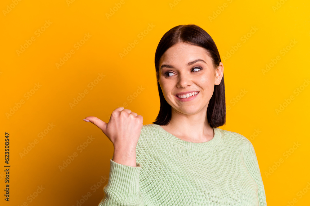 Photo of young cheerful girl look indicate finger empty space decision proposition isolated over yellow color background Photo of young cheerful girl look indicate finger empty space decision proposition isolated over yellow color background
