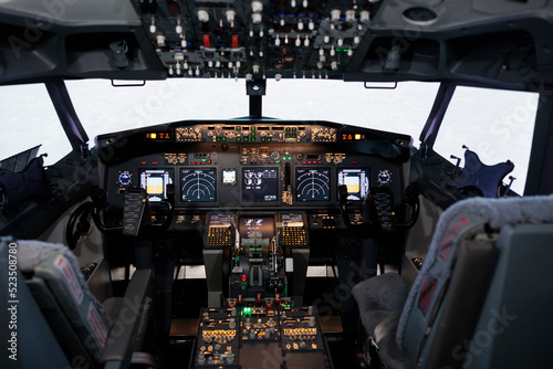 No people in airplane cockpit used by captain and copilot to fly, international airways jet with control panel buttons, steering wheel and dashboard command. Flying plane with engine throttle.