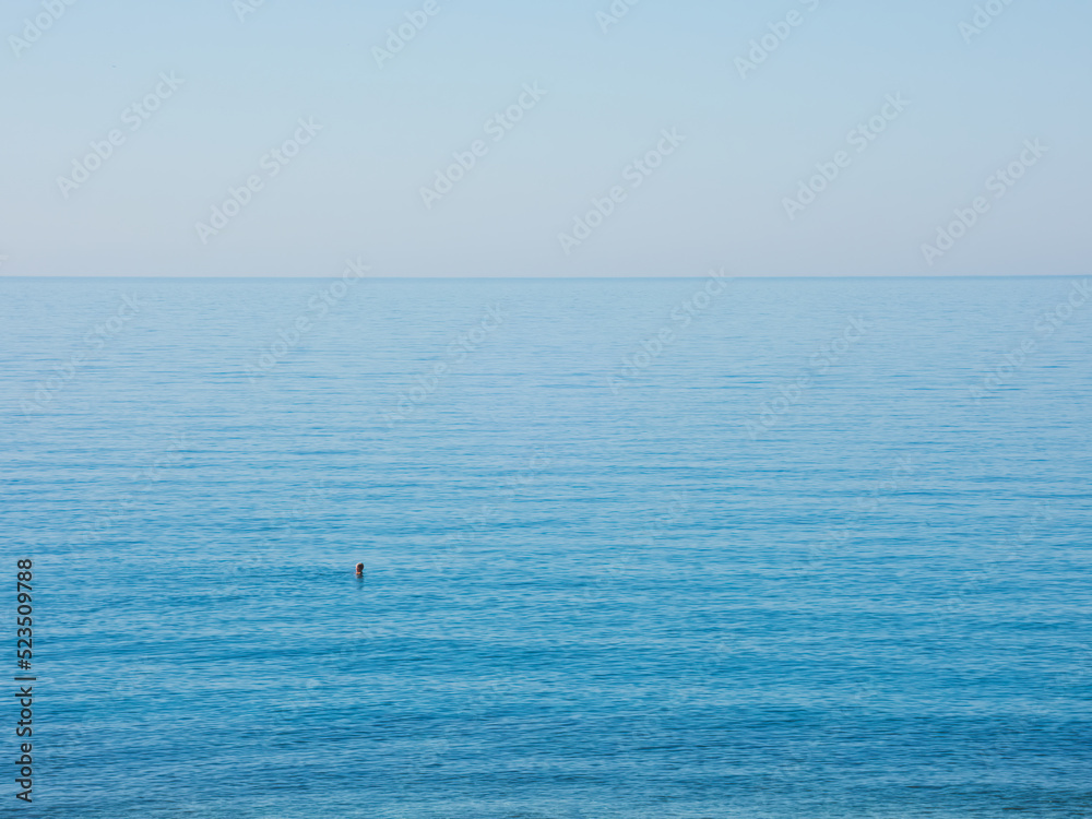 Man swimming in the mediterranean sea on a quiet sunny day