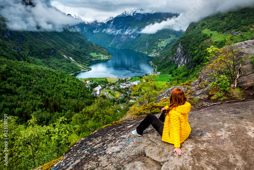 Woman in yellow sitting on the rock above Geiranger photo