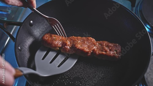 Flipping Ground Turkey Patty In Pan Using Slotted Turner And Fork. close up photo