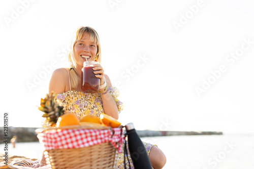 Cheerful young woman enjoy at tropical sand beach. Girl drinking juiceb photo