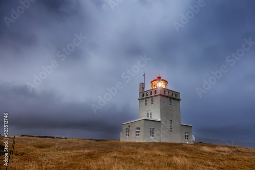Dyrholaey Lighthouse at blue hour in autumn, the most southerly point on mainland Iceland. Storm clouds are rolling in around the mountains behind