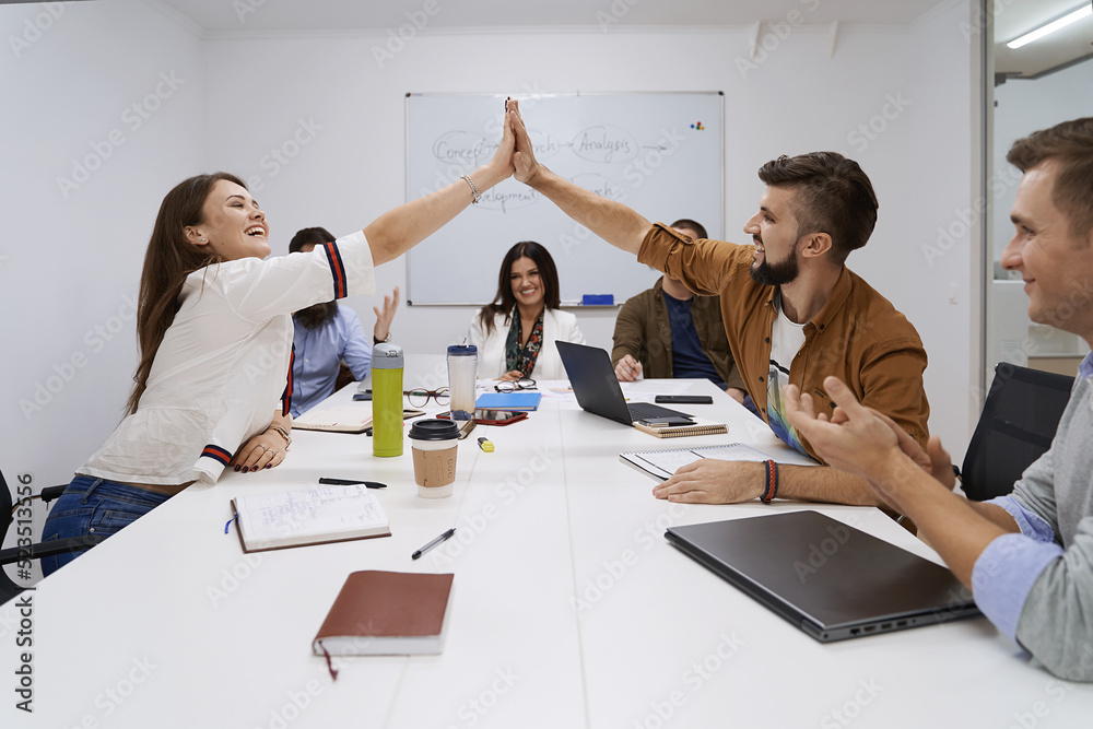 Happy team giving hightfive. Celebrating success with hi five. Coworkers friends touching hands after completed the work perfectly.