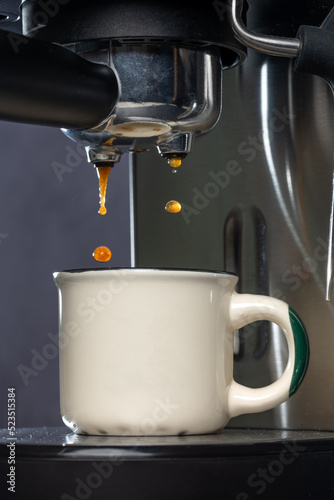 Coffee machine making espresso in a white cup.