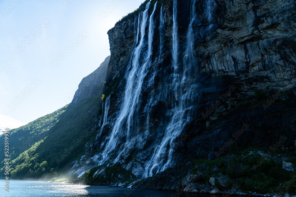 Famous seven sisters waterfall sliding down the cliff into Geirangerfjord on a sunny day