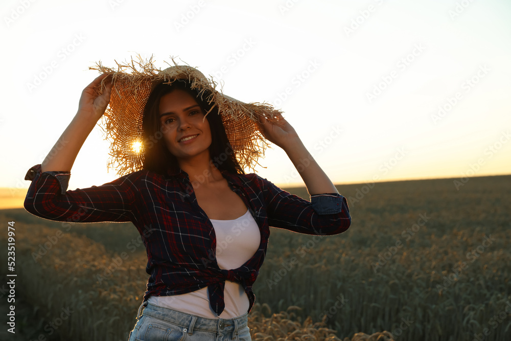 Beautiful young woman in straw hat among ripe wheat field on sunny day, space for text Beautiful young woman in straw hat among ripe wheat field on sunny day, space for text