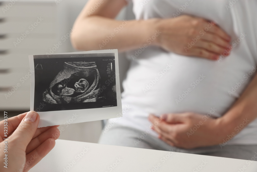 Pregnant woman having appointment in hospital, focus on doctor with ultrasound scan