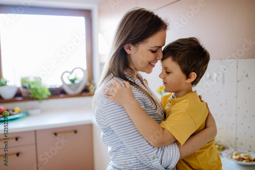 Happy young mother hugging her little son in kitchen at home.